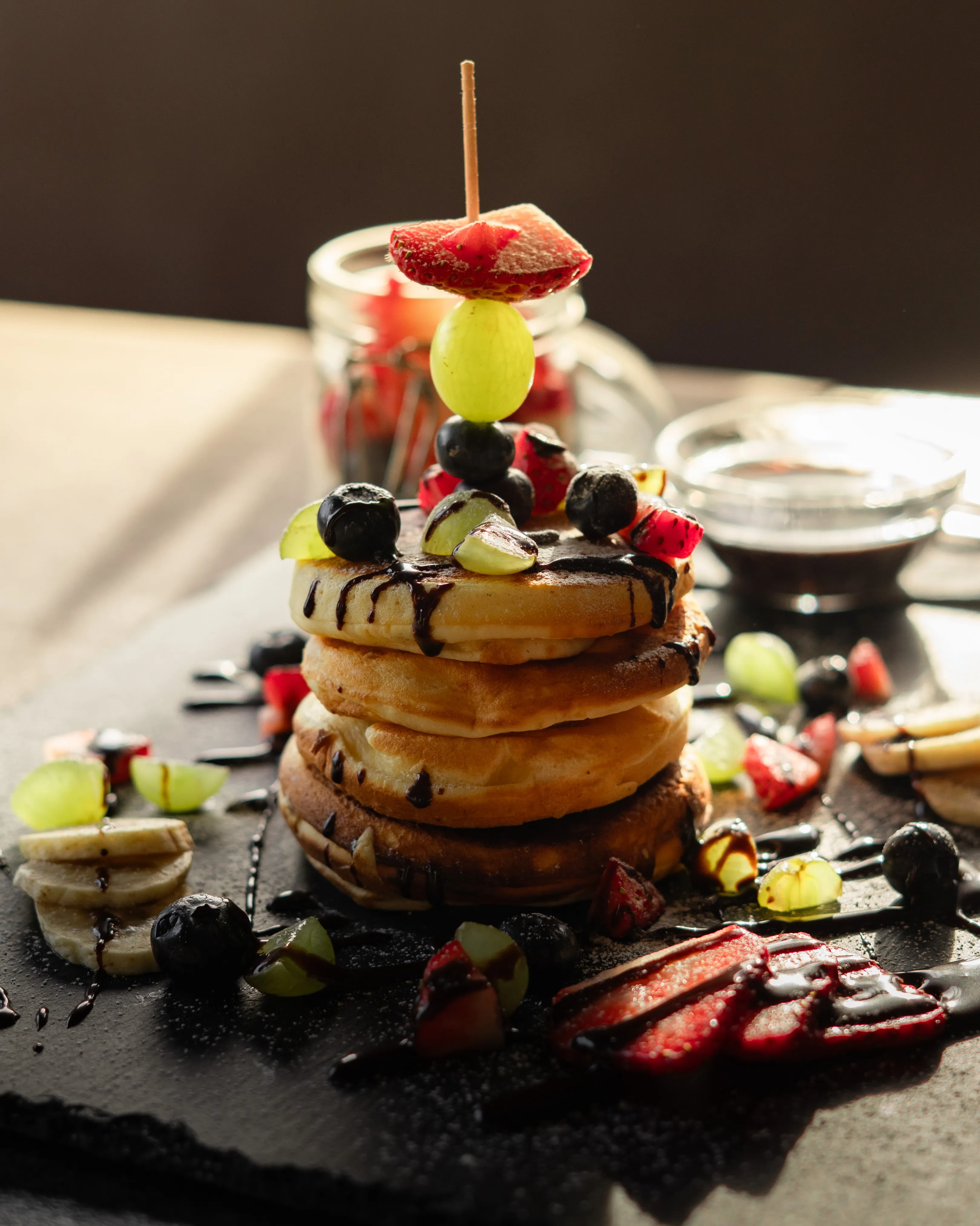 Pancake-Turm mit frischen Beeren, Banane und Schokosauce