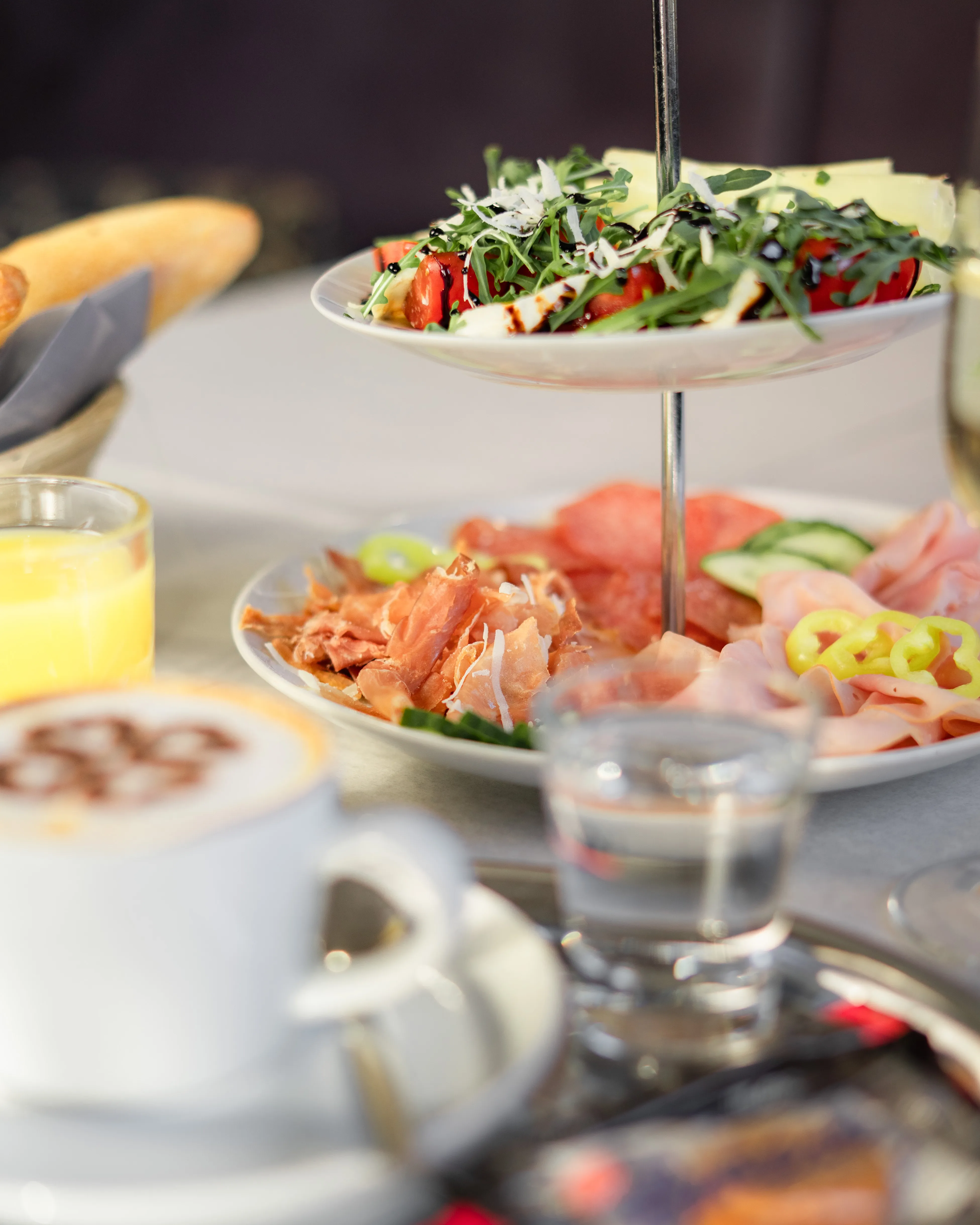 Etagere mit Aufschnitt, Salat und Cappuccino im Vordergrund