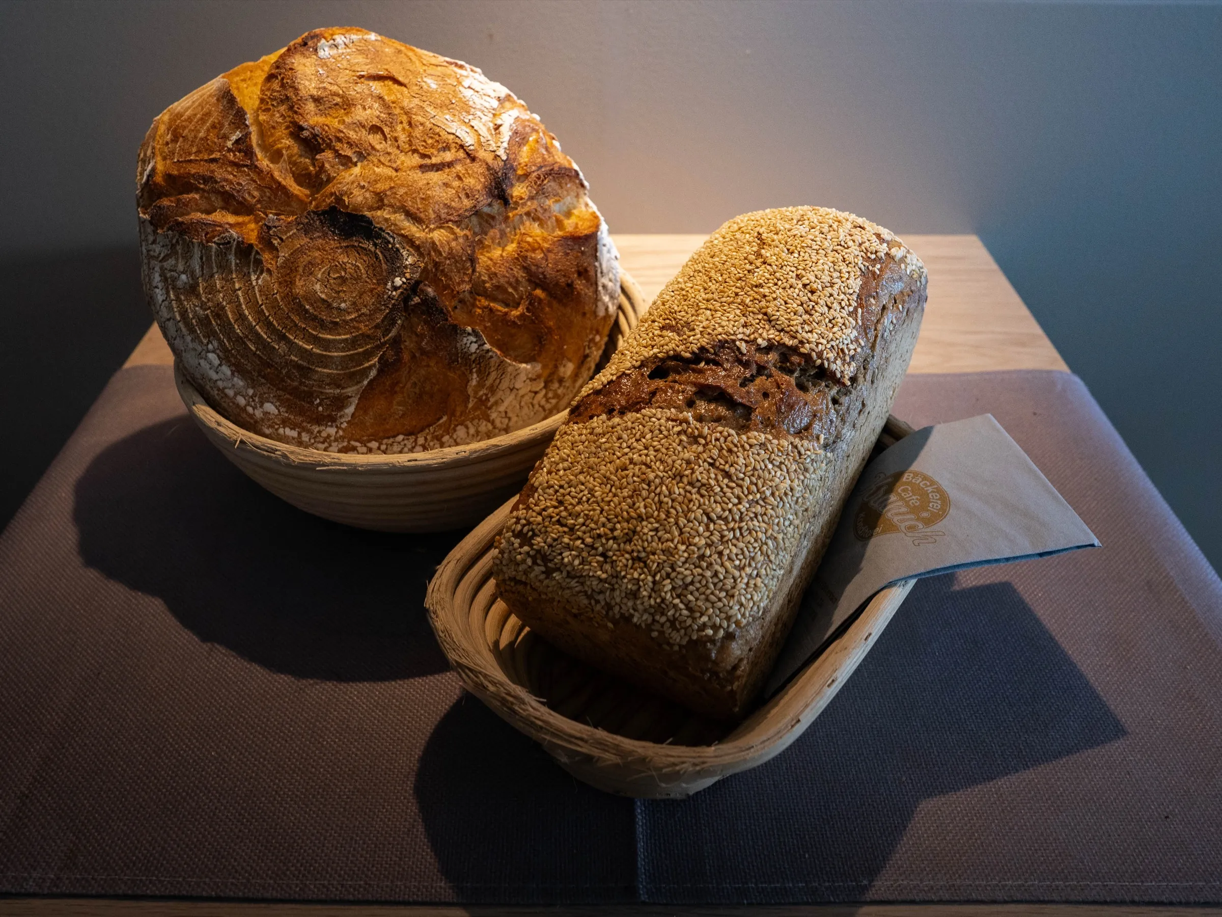 Roggenbrot mit Sesamkruste neben einem runden Roggenlaib